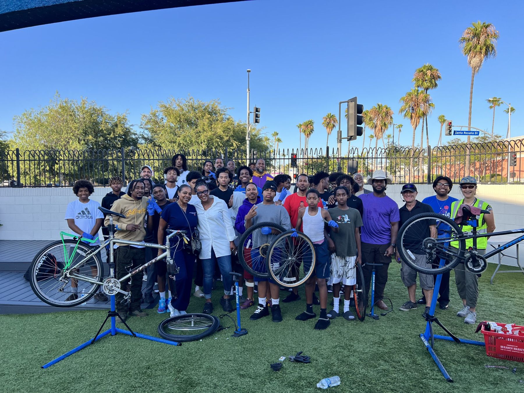 Youth, mentors, and volunteers holding bicycles at a community bike repair workshop